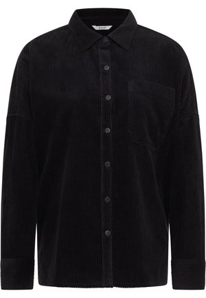 Cămașă din catifea neagră cu nasturi pe față, guler ascuțit, buzunar pe piept și mâneci cu manșete. Textura verticală cu nervuri adaugă profunzime.