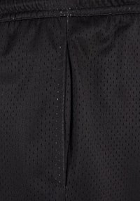 Shorts sportivi neri realizzati in tessuto retato traspirante con piccole perforazioni; vita elastica con una leggera lucentezza e dettagli cuciti.