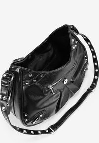 Bolso de hombro de cuero negro con herrajes plateados, tachuelas y un bolsillo con cremallera. Presenta una amplia abertura y una correa ajustable.