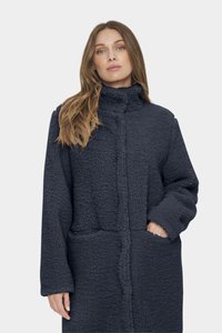 Fleecejacka i mörk marinblå med hög krage, långa ärmar och sidofickor; textil med en mjuk och mjuk yta.