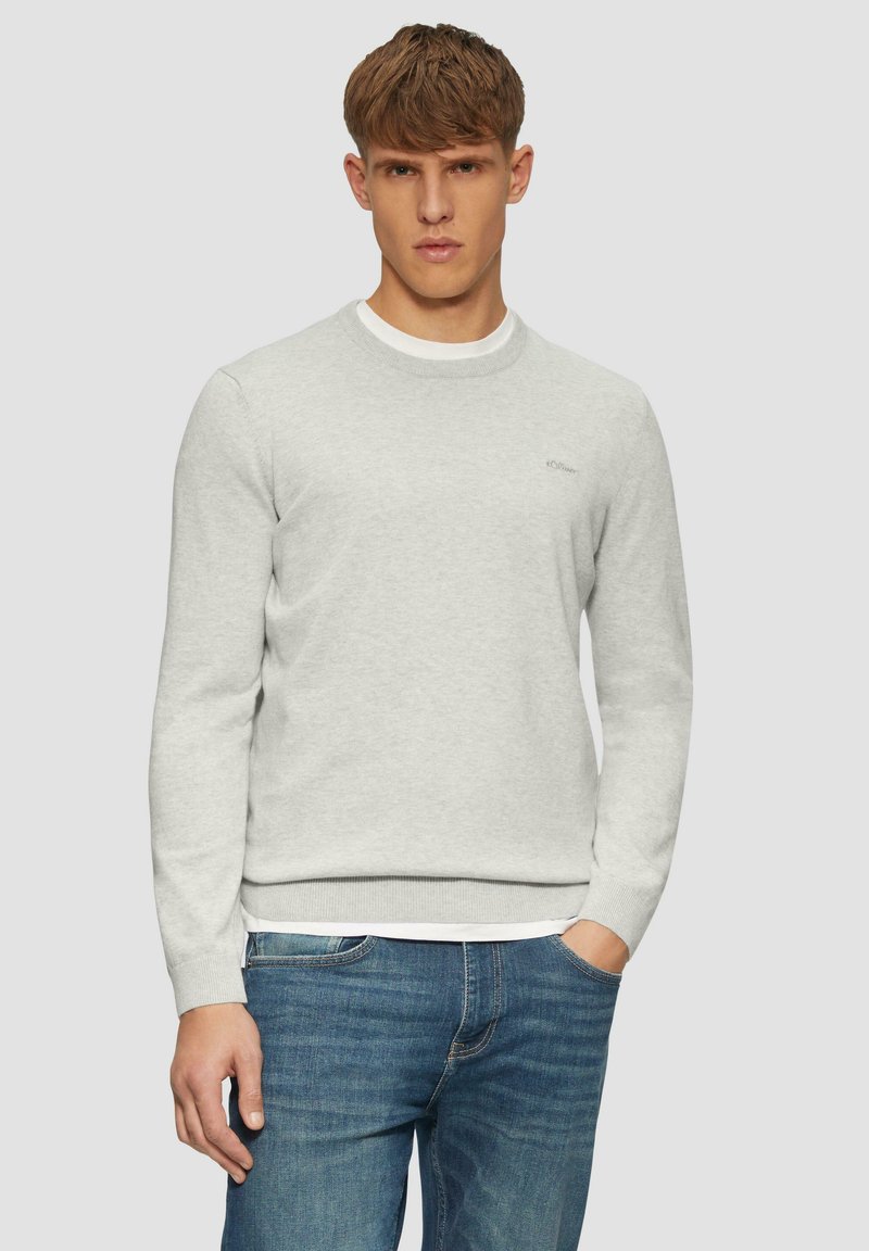 Lichtgrijze crewneck sweatshirt van textuurstof, met ribgebreide manchetten en zoom, gedragen over een wit T-shirt, gecombineerd met blauwe jeans.