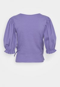 Blusa morada ajustada con mangas abullonadas, textura suave, detalles fruncidos en los puños y lazos laterales para ajuste. Diseño simple y acanalado.