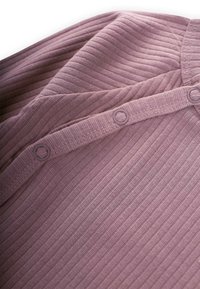 Rebrasti dukserica dugih rukava u boji mauve, s okruglim izrezom i dvije odgovarajuće okrugle dugmad duž otvorenog dijela. Mekani, teksturirani materijal.