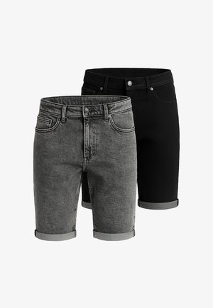 Lysfarvet, prikket t-shirt parret med mørke, oprullede denim shorts. Modellen bærer hvide sneakers med mesh-design.