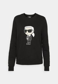 Svart sweatshirt i bomull med en tecknad grafisk bild av en karaktär i kostym och solglasögon, om given i vitt. Klassisk design med rund hals.