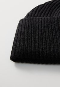 Schwarze Strickmütze mit vertikalen Rippen, aus einem weichen Wollmischgewebe gefertigt. Mit umgeschlagenem Rand und einer strukturierten Oberfläche.