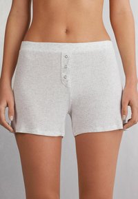 Lichtgrijze geribde shorts van zacht materiaal, met een knoopsluiting aan de voorkant met drie zilveren knopen en een comfortabele elastische tailleband.