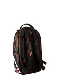 Mochila a cuadros en negro y marrón con correas acolchadas y un diseño de dientes de tiburón en rojo, blanco y negro en el panel lateral inferior.