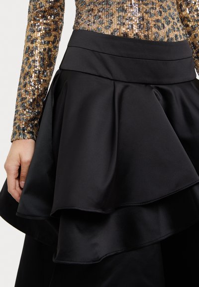 Fustă din satin negru cu un design stratificat și volanat. Talia este netedă, complementând textura fluidă a materialului.