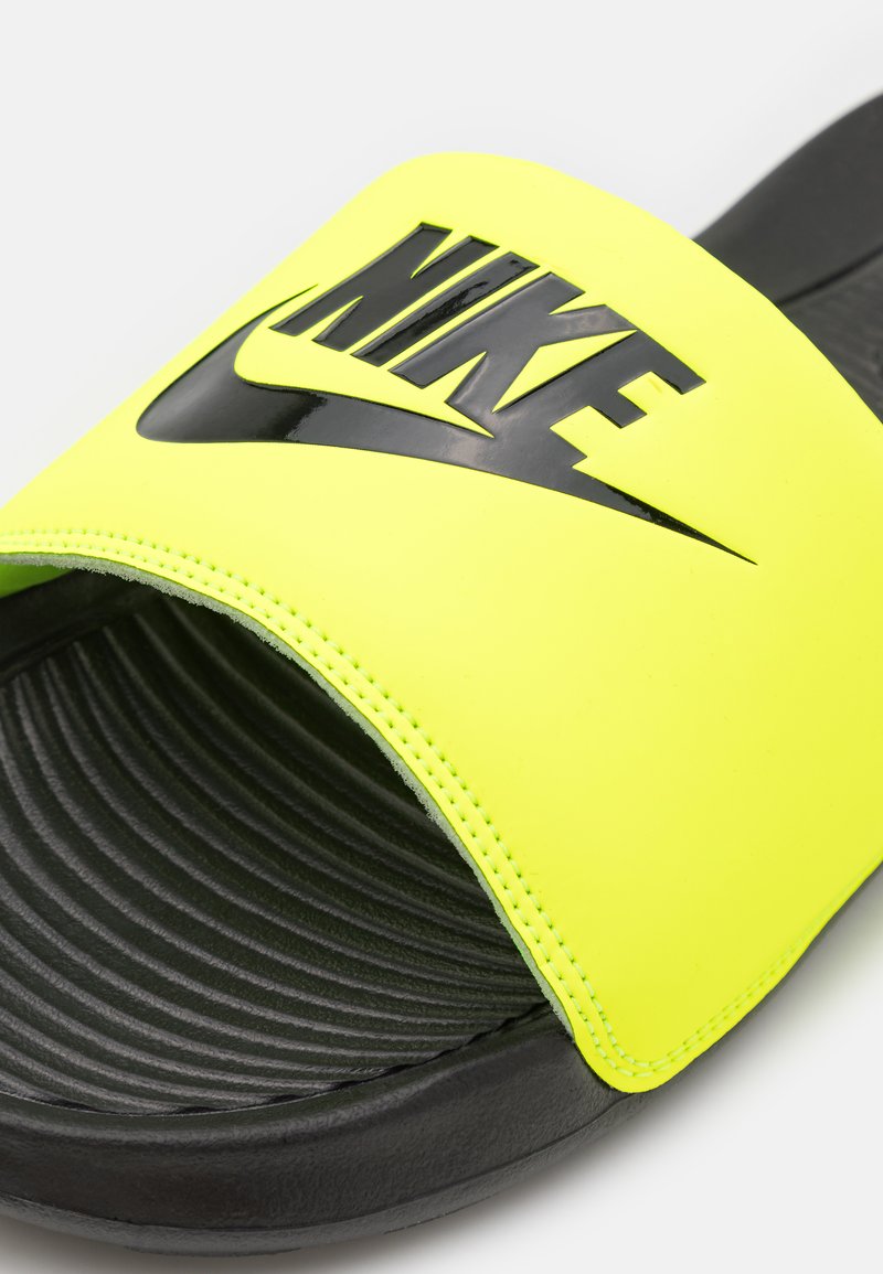 Infradito Nike con una parte superiore gialla neon brillante, logo nero e soletta nera texturizzata. La fascia è liscia con bordi cuciti.