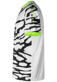 Camicetta bianca con un audace motivo astratto nero, dettagli verdi sul colletto e sulle maniche, e tre bottoni decorativi.