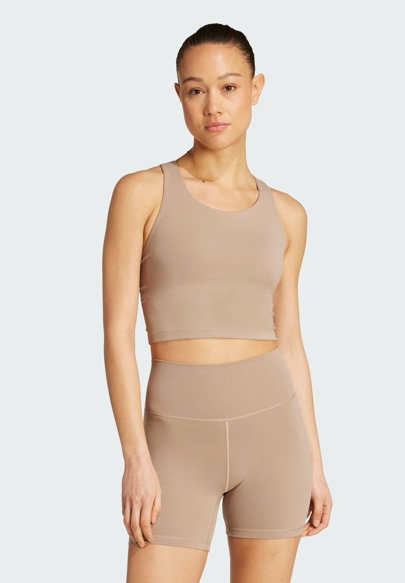 Conjunto de sujetador deportivo y pantalones cortos de cintura alta en beige claro. Tejido suave, diseño ajustado, tirantes anchos y costuras limpias. Estilo minimalista.