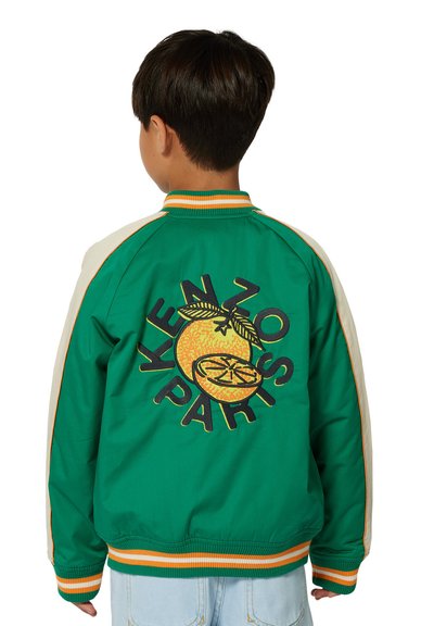 Groene bomberjack met crèmekleurige mouwen heeft een oranje vruchtengrafiek en de tekst "KENZO PARIS", afgewerkt met oranje strepen.
