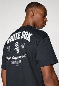Crna pamučna majica s natpisom "WHITE SOX" velikim bijelim slovima, otiscima logotipa i tekstom koji detaljno opisuje "Major League Baseball" i "Chicago, IL."
