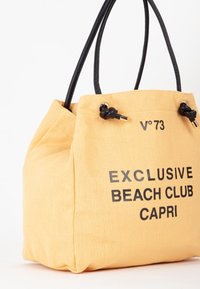 Borsa a tracolla in tela gialla con testo nero: "EXCLUSIVE BEACH CLUB CAPRI." Dotata di manici in pelle nera e dettagli annodati.