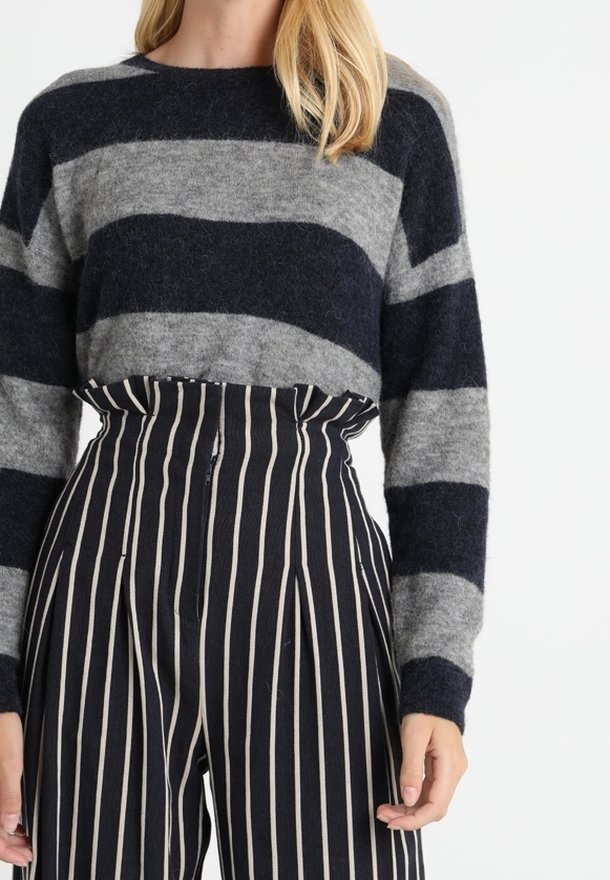Grå och marinblå randig tröja med rund hals och långa ärmar, kombinerad med hög midja, vida randiga byxor i marinblått och kräm.