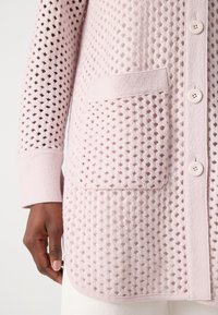 Lichtroze cardigan met een textuur gebreide patroon, lange mouwen, knoopsluiting en een voorzak. Zacht materiaal met een comfortabele feel.