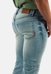 Jeans slim-fit di denim blu chiaro. Presentano un'etichetta in pelle in vita e due tasche posteriori con dettagli cuciti.
