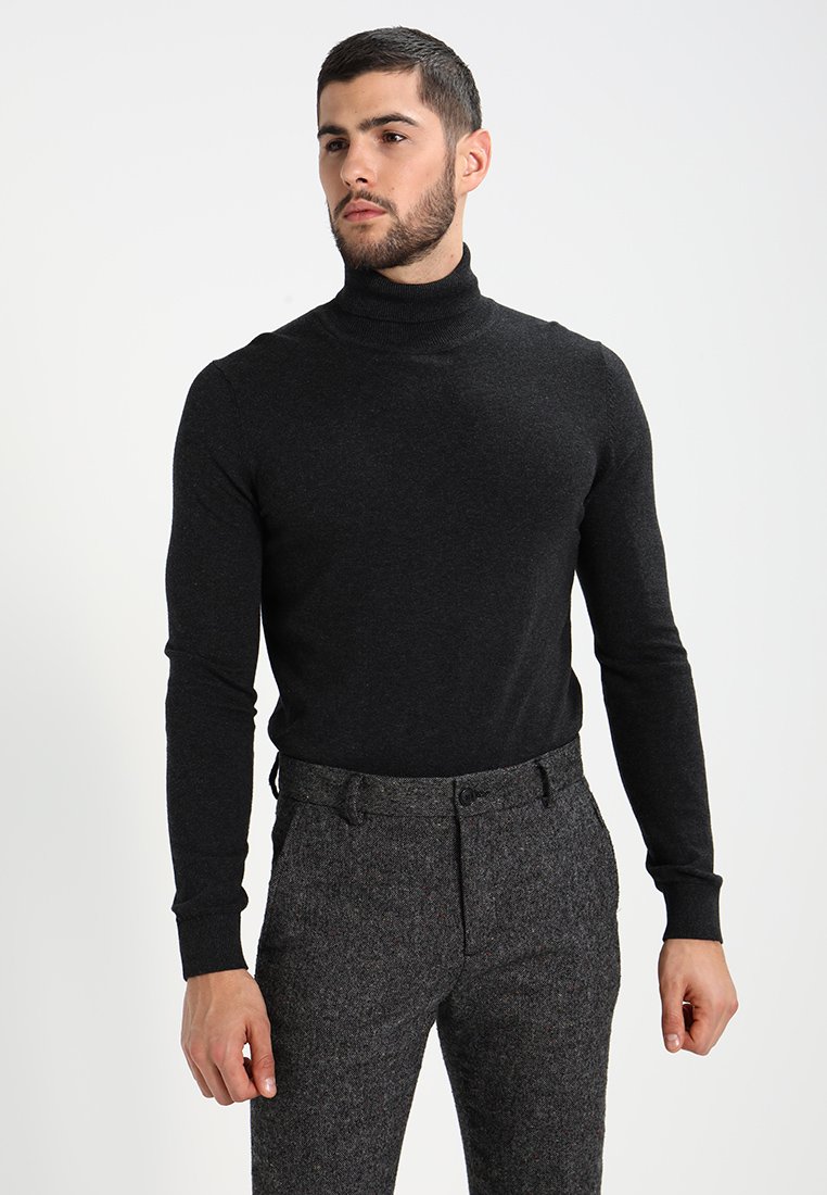 Zwarte turtleneck trui van zacht materiaal, met een getailleerd ontwerp en lange mouwen, gecombineerd met gestructureerde grijze broek.