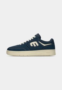 Navy blue sneakers made of suede and leather with a white rubber sole, featuring contrasting accents and distinctive logo on the sides.