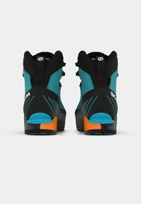 Par de botas de caminhada azuis e pretas com detalhes laranja vistas por trás sobre um fundo branco.