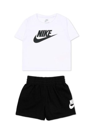 Chemise blanche à manches courtes avec logo Nike noir et short à taille élastique noire avec logo Nike blanc sur la jambe gauche.