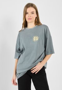 Relaxed-fit, short-sleeve t-shirt in muted gray cotton, featuring a small yellow sun design on the left chest area.