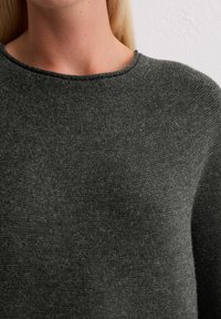 Grauer Strickpullover mit glatter Textur, rundem Ausschnitt und dezenten Nähdetails, gekürzt, um den oberen Teil zu betonen.
