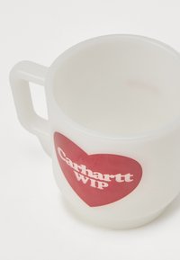 Sateen lasimuki, jossa on valkoinen kahva ja suuri punainen sydäntunnus, jossa on valkoista "Carhartt WIP" -tekstiä.