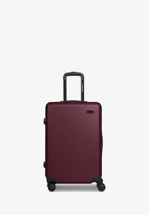 Maleta rígida color granate con asa telescópica y cuatro ruedas giratorias, ubicada en posición vertical sobre fondo blanco.