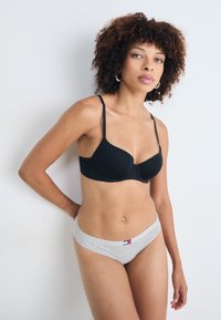Sutien negru cu padding, cu bretele ajustabile, și chiloți hipster gri din bumbac, având un mic etichetă cu logo. Textură netedă, design simplu.
