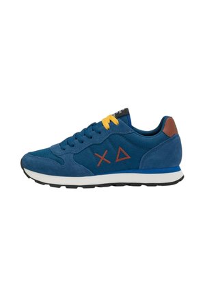 Niebieski zamszowy sneaker z brązowymi symbolami logo, żółty detal sznurowadeł, biała podeszwa i czarny bieżnik, widziany z boku na białym tle.