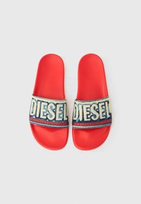 Punased liuglejad pehme karvaga paelaga, millel on suured valged tähed "DIESEL" ning sinise teksataolise taustaga punaste detailidega.