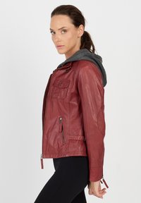 Rote Lederjacke mit grauem Kapuzen, Reißverschluss vorne, Seitentaschen und dekorativen Beschlägen. Verfügt über einen taillierten Schnitt und eine strukturierte Oberfläche.