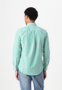 Cămașă cu mâneci lungi, în dungi verzi și albe, cu guler tip button-down, având un tiv curbat și manșete cu un singur buton.