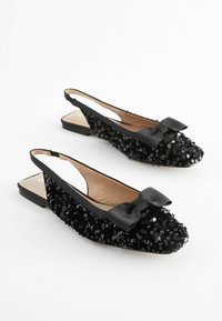Ballerines à brides arrière noires ornées de sequins, avec un bout pointu, un accent en satin en forme de nœud et une doublure intérieure lisse sur une semelle plate.