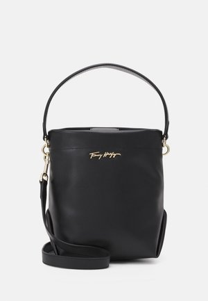 Black leather shoulder bag with gold Tommy Hilfiger logo, short handle, and detachable long strap on plain background.