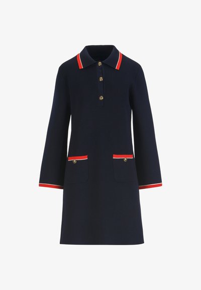 Tmavomodré šaty s dlhým rukávom s červeným a bielym lemovaním na golieri, manžetách, dvoch predných vreckách a zlatými gombíkmi na prednej strane.