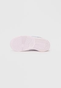 Nike tornacipő talpa kerek mintázattal, főleg világos rózsaszínű, textúrázott részletekkel és gyenge logónyomattal.