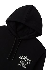 Czarna bluza z kapturem z grafiką niedźwiedzia na przodzie. Posiada sznurek w kapturze i miękką teksturę materiału. Projekt podkreśla prostotę i wygodny styl. 