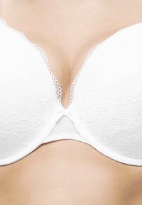 Witte kanten beha met een diepe halslijn, gladde cups en een bloemenpatroon. Voorzien van een delicate rand en een centrale sluiting voor een veilige pasvorm.