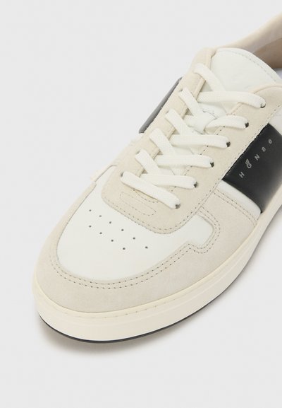 Gray suede and white leather sneaker with black accents, perforated toe box, cream laces, and a flat rubber sole.