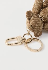 Brązowy brelok w wzory z motywem niedźwiedzia. Złote elementy metalowe obejmują łańcuszek, karabińczyk i kółko na klucze.