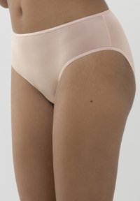 Beżowe majtki damskie, wykonane z gładkiego, półprzezroczystego materiału z miękkim elastycznym pasem i minimalnymi szwami, co zapewnia bezszwowy wygląd.