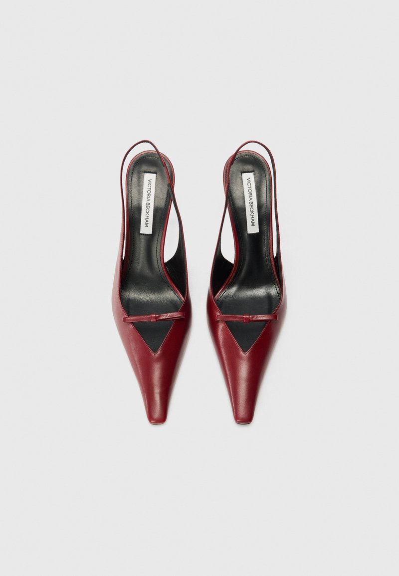 Röda läderslingbackklackar med spetsig tå, svarta detaljer och en smal rem. Texturerad yta med en slät finish.