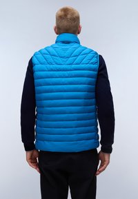 Blå kviltad v�äst med hög krage, med horisontell sömnad och en enhetlig mörk marinärm. Slät textur, lättviktsdesign.