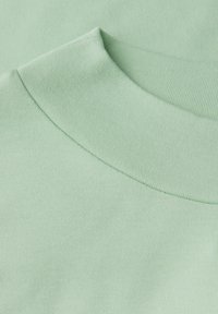 Jasnozielony bawełniany T-shirt z kołnierzykiem o ribbowanej strukturze, z zaokrąglonym dekoltem i gładkimi detalami szycia.