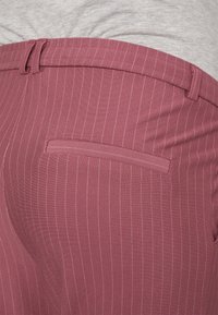 Bordo hlače s prugicama od glatkog materijala, s pojasom s petljama za remen i jednim stražnjim džepom s ušivenim dizajnom.