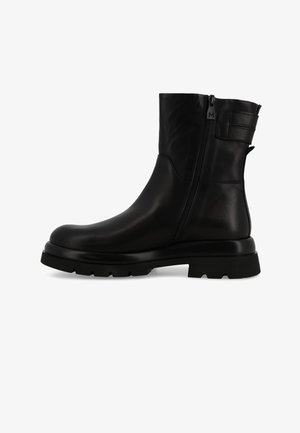 Stivale alla caviglia in pelle nera con punta rotonda, chiusura con zip laterale e suola in gomma spessa e testurizzata. Presenta un etichetta di estrazione sul retro.