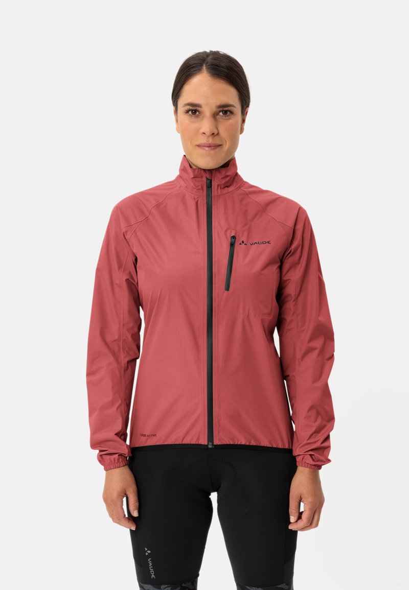 Rode lichtgewicht jack met lange mouwen, hoge kraag en zwarte rits. Voorzien van logo op de borst en elastische manchetten. Gecombineerd met zwarte fietsshorts.